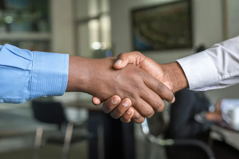 Two professionals shaking hands across a desk