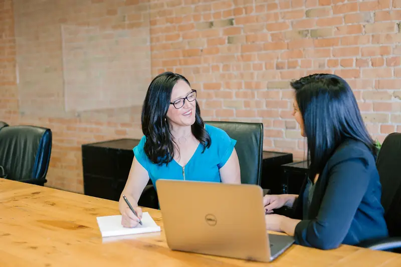 A recruiter interviews a candidate across a desk with a laptop