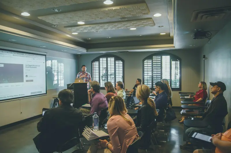 A trainer presents to a room of seated participants during a workshop